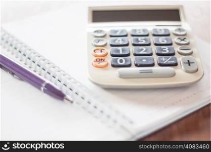 Calculator and pen on notebook, stock photo