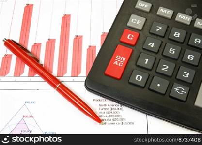calculator and red pen over a business chart
