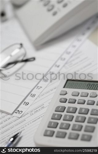 Calculator and telephone with eyeglasses on paper