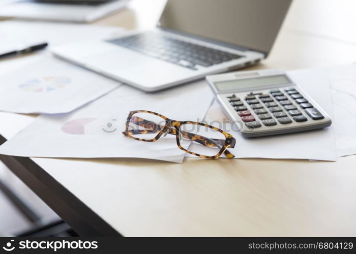 calculator, business document and laptop computer notebook on wooden table