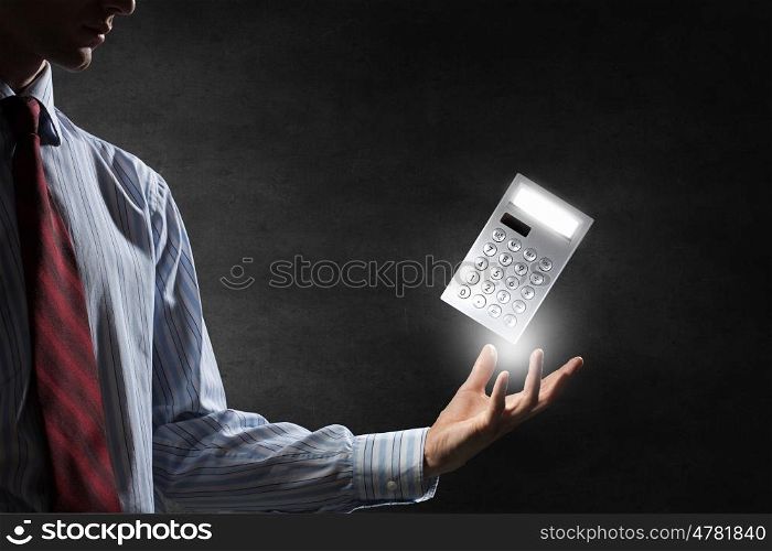 Calculator in palm. Man hand with calculator on dark background