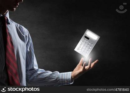 Calculator in palm. Man hand with calculator on dark background