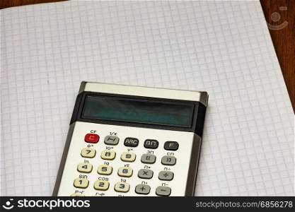 Calculator lying on a sheet of paper into the cell from a notebook for records