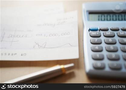 Calculator pen and filled cheque on table close-up
