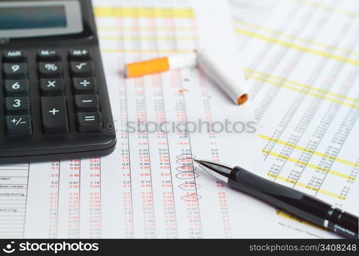 Calculator, pen with cigarette on financial data.