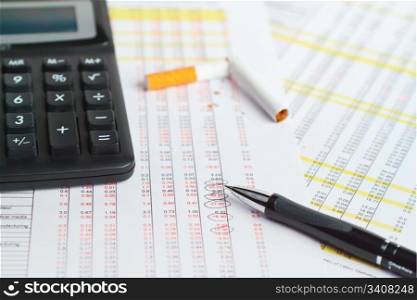 Calculator, pen with cigarette on financial data.