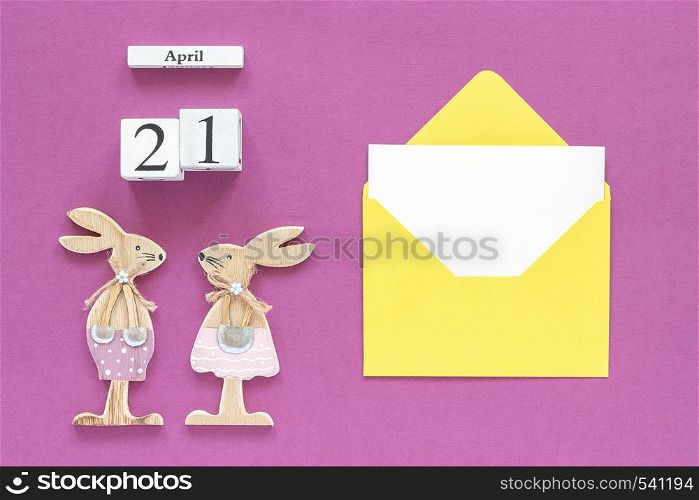 Calendar April 21, pair wooden easter bunnies, yellow envelope with blank card on purple paper background Concept Catholic Easter Mockup Template for lettering, text or your design Top View.. Calendar April 21, pair wooden easter bunnies, yellow envelope with blank card on purple paper background Concept Catholic Easter Mockup Template for lettering, text or your design Top View