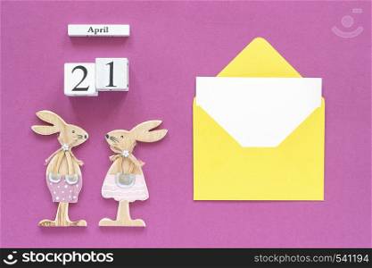 Calendar April 21, pair wooden easter bunnies, yellow envelope with blank card on purple paper background Concept Catholic Easter Mockup Template for lettering, text or your design Top View.. Calendar April 21, pair wooden easter bunnies, yellow envelope with blank card on purple paper background Concept Catholic Easter Mockup Template for lettering, text or your design Top View