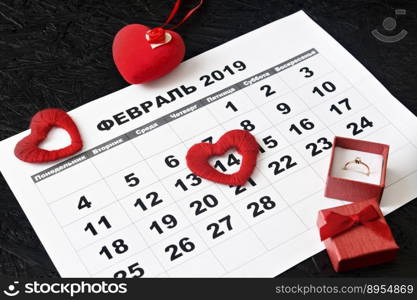 Calendar page with red hearts and a gift on February 14, Valentine’s Day on a black background. Valentine card. Calendar for February in Russian.. Calendar page with red hearts and a gift on February 14, Valentine’s Day on a black background. Valentine card. Calendar for February in Russian