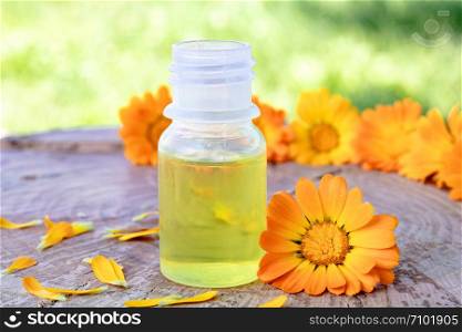 calendula essential oil near the yellow flowers of calendula on a wooden background in nature. Extract of tincture of calendula. Medicinal plants. calendula essential oil near the yellow flowers of calendula on a wooden background in nature. Extract of tincture of calendula.
