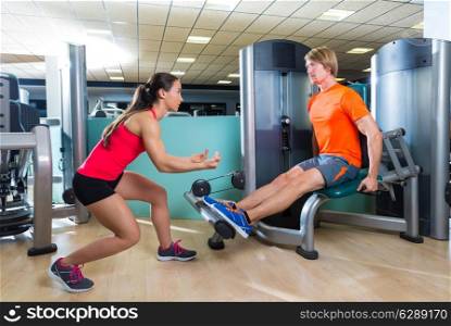 Calf extension man at gym exercise machine workout and personal trainer woman
