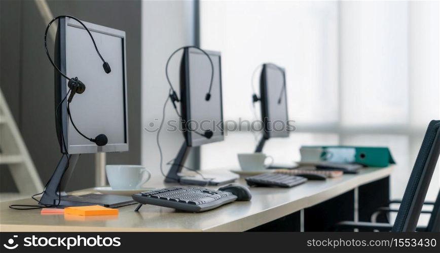 Call center computers and headsets all in office. Telemarketing, customer support agent provide service on telephone video conference call.