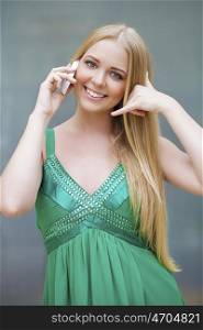 Call Me. Beautiful happy woman in green dress making a call me gesture, indoor