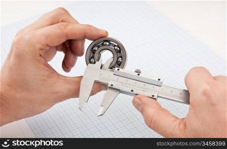 callipers with bearing in hand on a background of graph paper