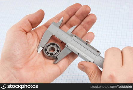 callipers with bearing in hand on a background of graph paper