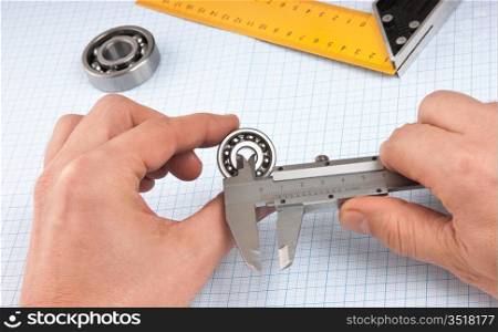 callipers with bearing in hand on a background of graph paper