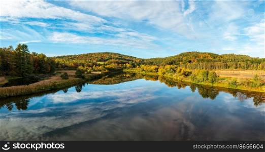 Calm and wide Ottauquechee river flows towards Quechee Gorge in Vermont with fall colors. Ottauquechee river near Quechee gorge in the fall