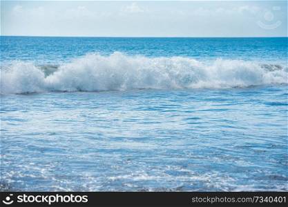 Calm blue seascape with white surf wave on foreground 