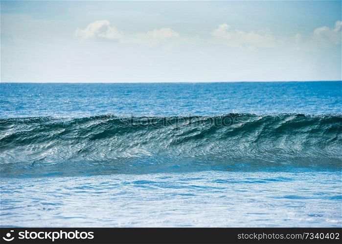 Calm blue seascape with white surf wave on foreground
