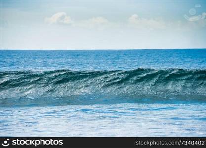 Calm blue seascape with white surf wave on foreground
