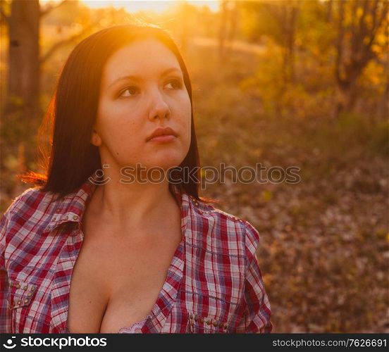 Calm face of the nice girl resting in autumnal woodland backlit