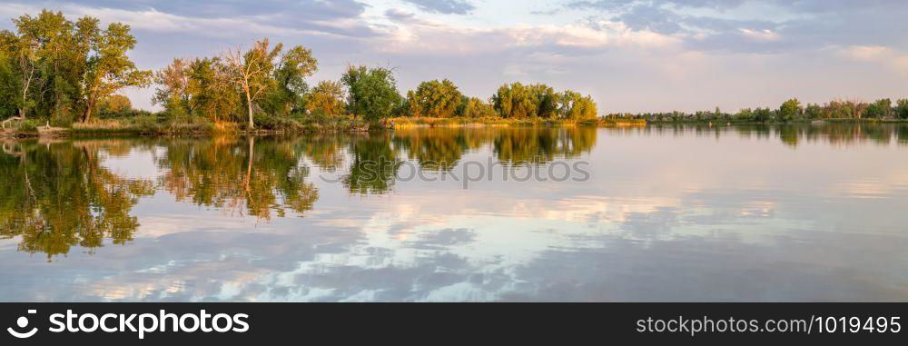 Calm fishing lake in northern Colorado sunset reflection, summer scenery panoramic banner