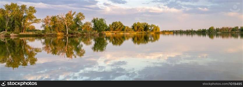 Calm fishing lake in northern Colorado sunset reflection, summer scenery panoramic banner