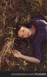 Calm girl in lying in tall grass in the fields, copyspace on top