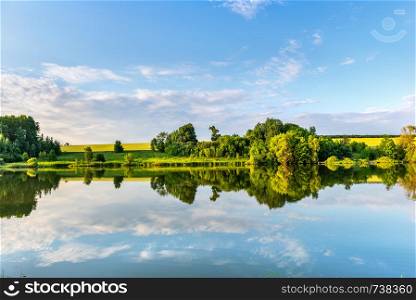Calm river in spring at sunrise with reflection of beautiful sky. Calm river in spring