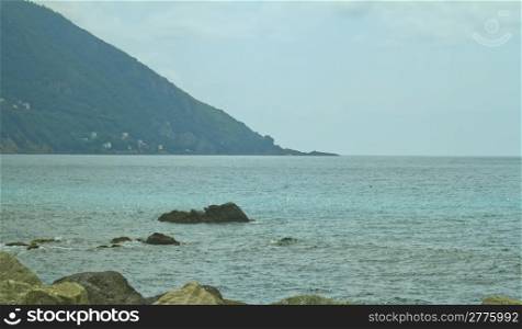 Calm sea scene with rocks and far coastline
