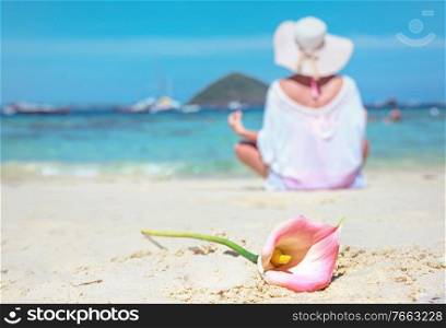 Calm woman meditating on a beach, beautiful flower