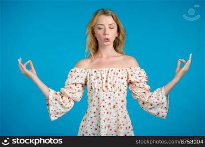Calm woman relaxing, meditating. Girl calms down, breathes deeply with mudra om on blue studio background.. Calm woman relaxing, meditating. Girl calms down, breathes deeply with mudra om on blue studio background