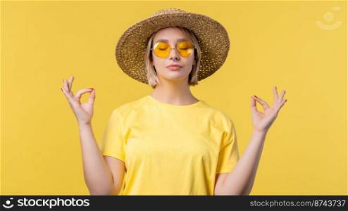 Calm woman relaxing, meditating, refuses stress. Sunny girl breathes deeply, calms down yellow studio background. Yoga, moral balance, zen concept. High quality photo. Calm woman relaxing, meditating, refuses stress. Sunny girl breathes deeply, calms down yellow studio background. Yoga, moral balance, zen concept.