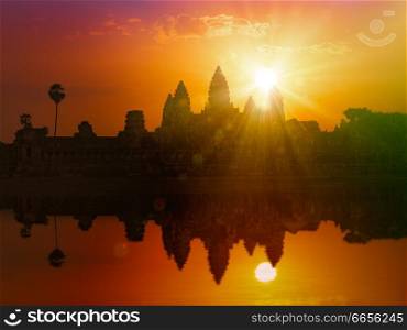 Cambodia landmark Angkor Wat silhouette with reflection in water on sunset. With lens flare and light leak. Angkor Wat on sunset