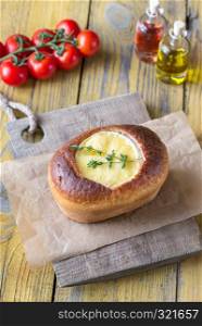 Camembert bread bowl with fresh tomatoes on the wooden background