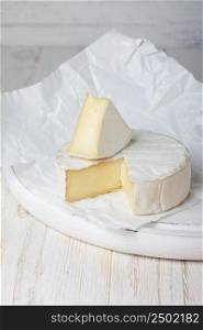 Camembert cheese on cutting board, focus on sliced piece