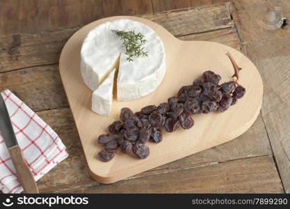 Camembert cheese with a twig of muscat raisins on a heart shaped cheese board