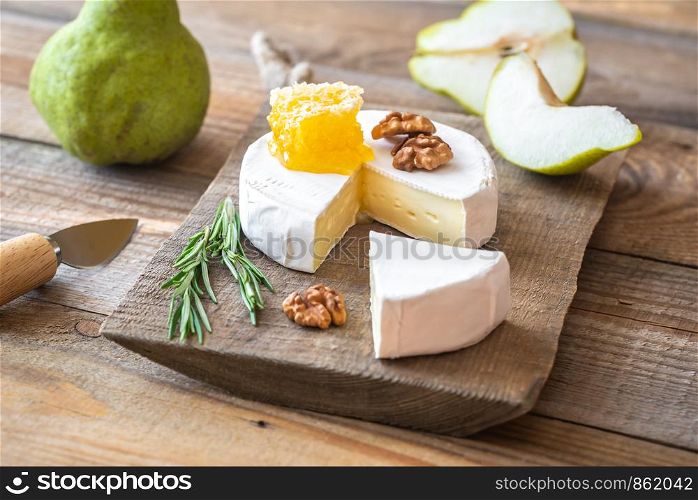 Camembert cheese with fresh pears and walnuts on the wooden board