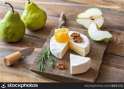 Camembert cheese with fresh pears and walnuts on the wooden board