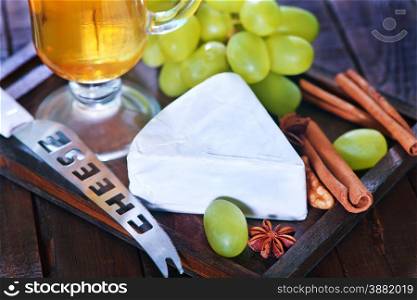 camembert cheese with green grape on the wooden board