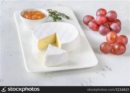 Camembert with apricot jam and bunch of grapes on the serving plate
