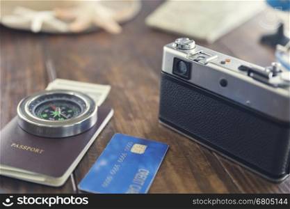 camera, hat, compass, passport, credit card, banknote money, globe, map and starfish figurine on wooden table for use as traveling concept (vintage tone and selected focus)