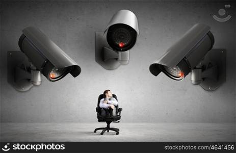 Camera keep an eye on man. Young businessman in room under CCTV camera control