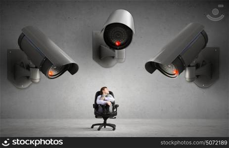 Camera keep an eye on man. Young businessman in room under CCTV camera control