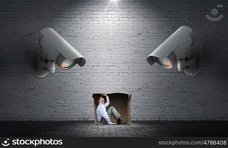 Camera keep an eye on man. Young scared man in room under CCTV camera control
