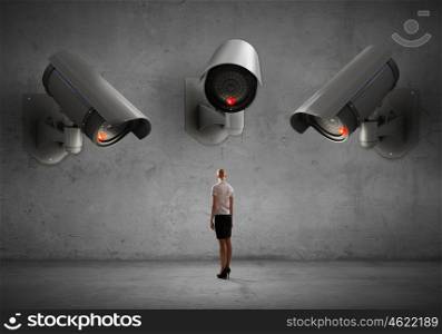 Camera keep an eye on woman. Young businesswoman in room under CCTV camera control