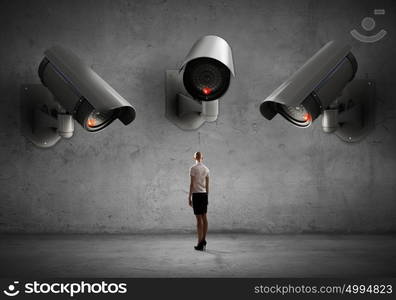 Camera keep an eye on woman. Young businesswoman in room under CCTV camera control