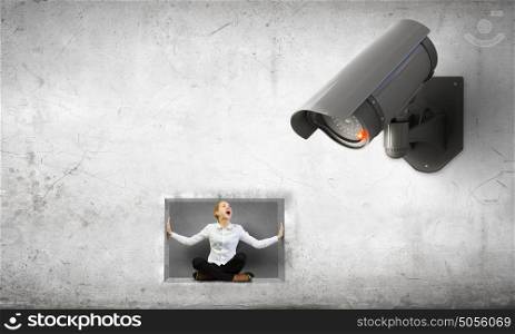 Camera keep an eye on woman. Young scared woman in room under CCTV camera control