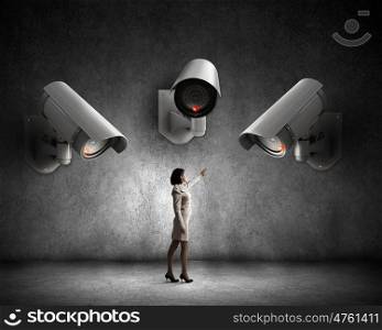 Camera keep an eye on woman. Young woman in room under CCTV camera control