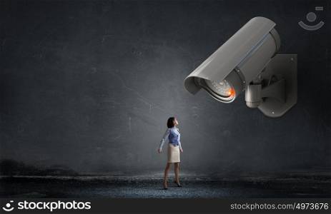 Camera keep an eye on woman. Young woman in room under CCTV camera control